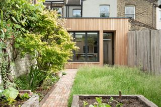 A rear garden with a timber clad extension featuring a large window