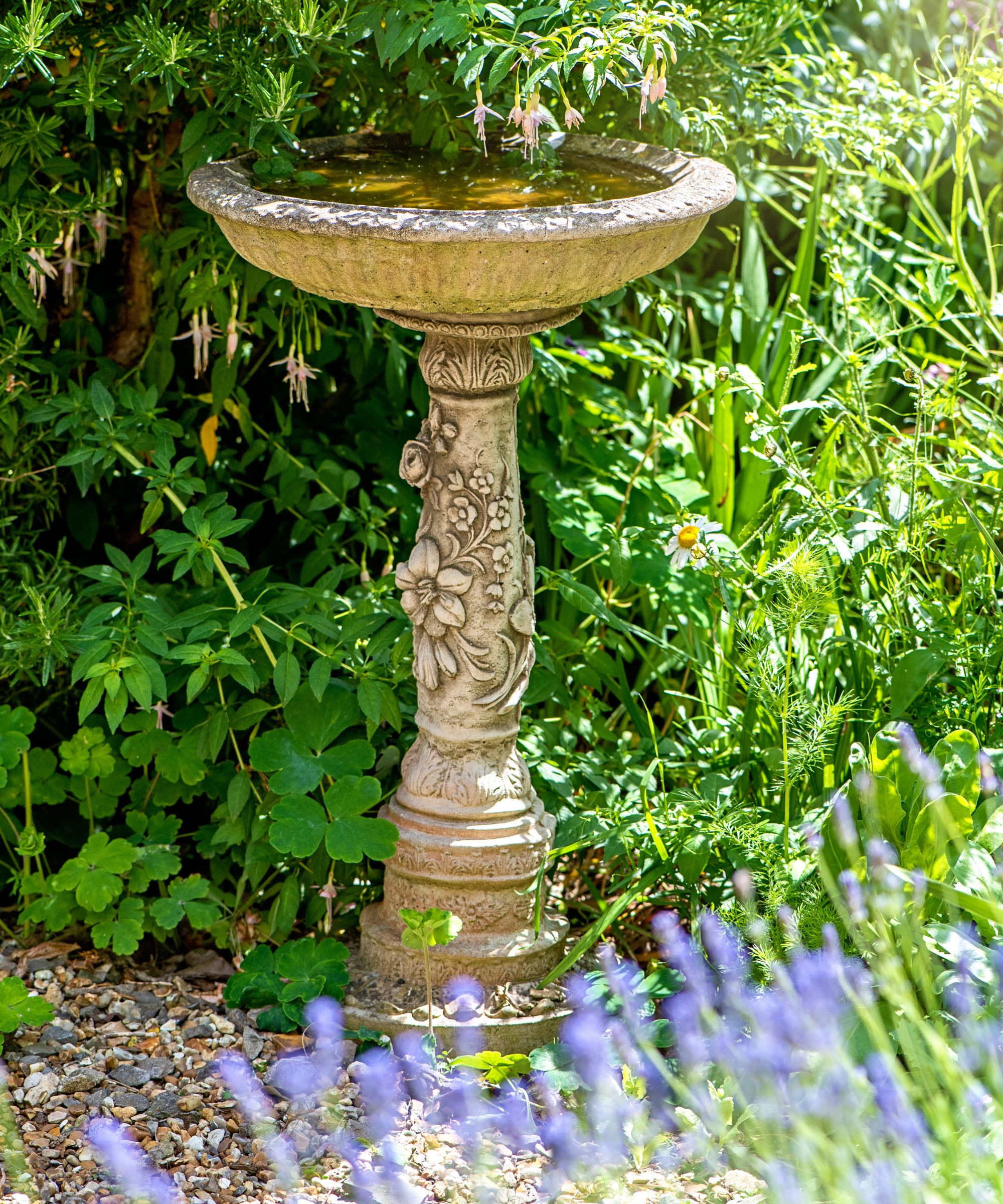 Stone birdbath surrounded by wildflowers