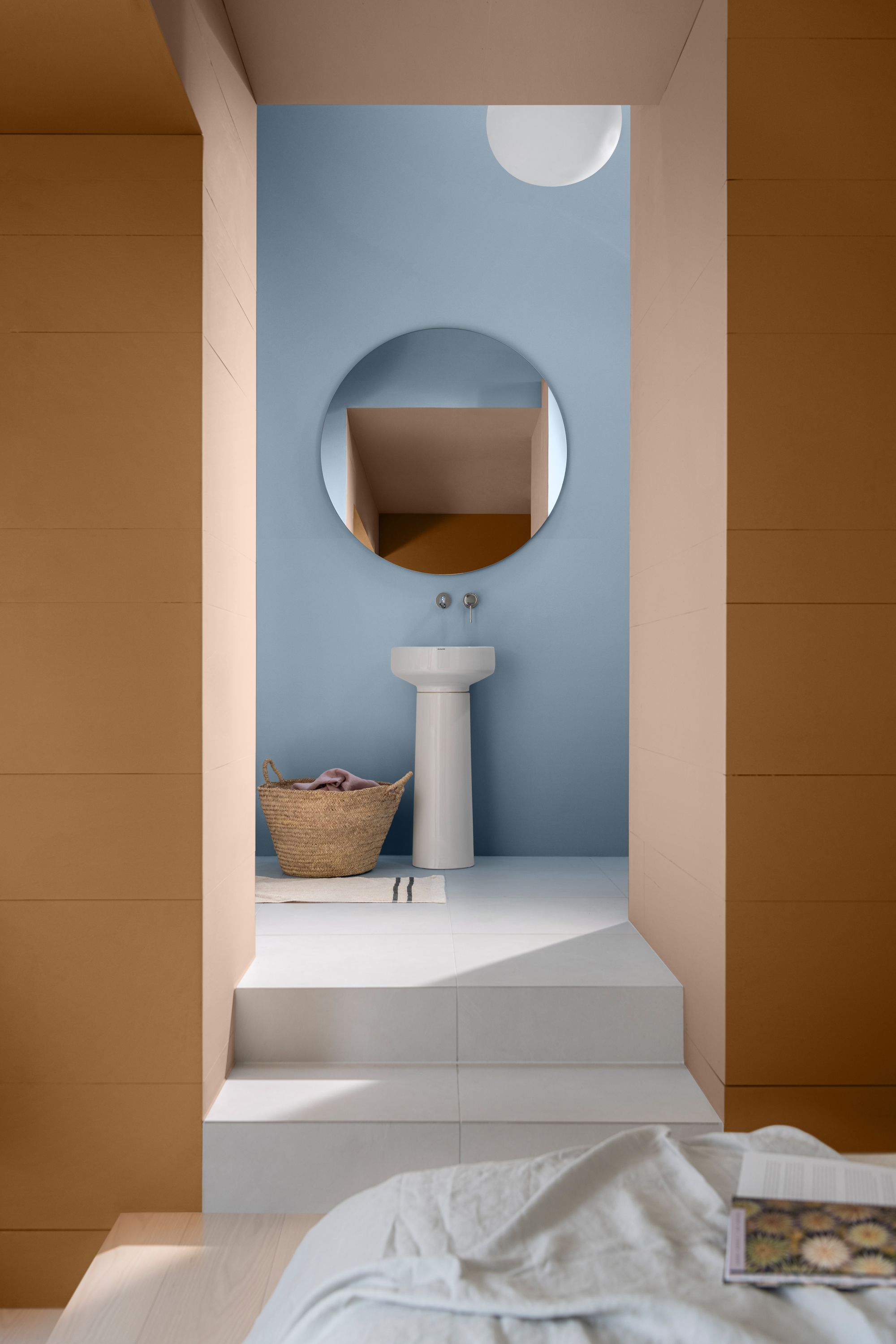 Image of a burnt orange bedroom with an open doorway with white steps that lead up to a light blue bathroom. 