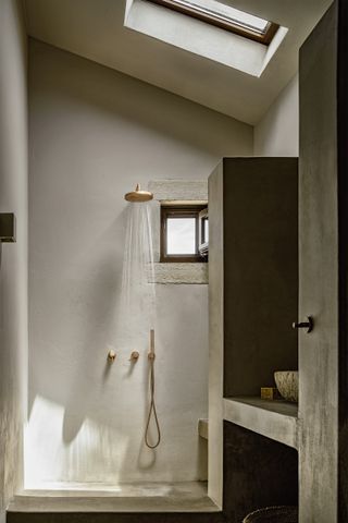 A grey shower room with sloped ceiling and sky light