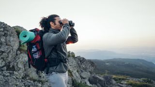 Backpacker on mountain using binoculars