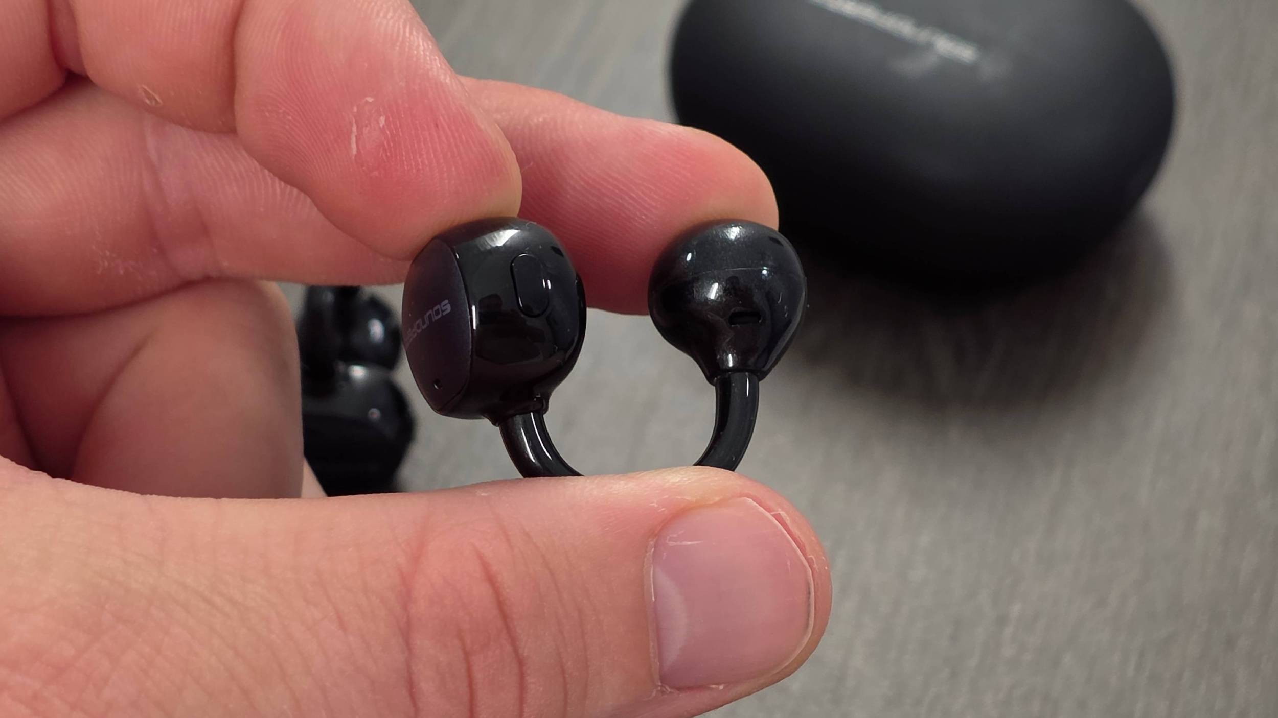 The Soundpeats Pop Clip2 earbud in a man's hand.