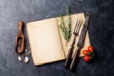 Cookbooks: book on kitchen side with tomatoes, rosemary and cutlery
