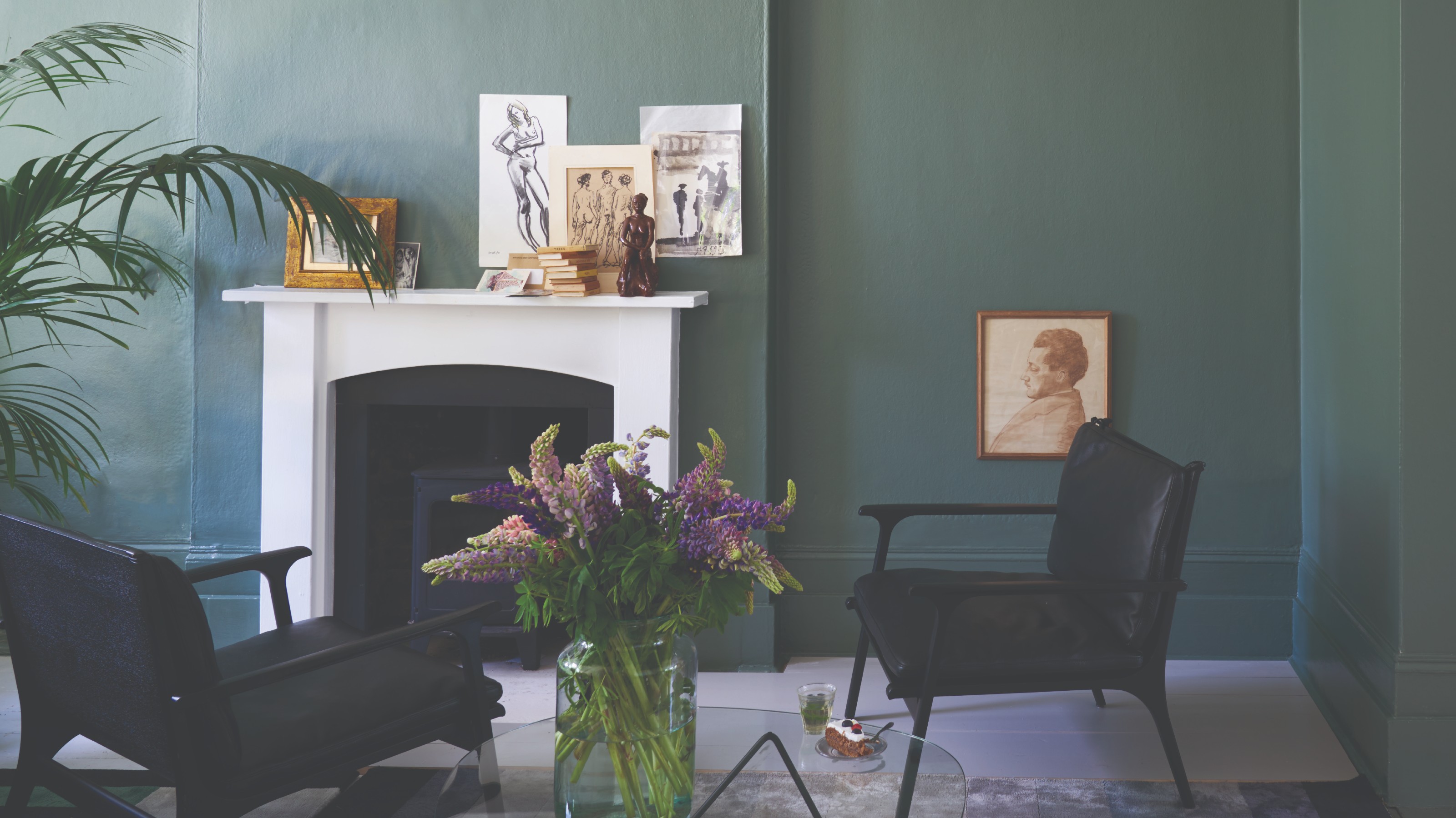 A living room painted in Farrow & Ball's Green Smoke with a white fireplace