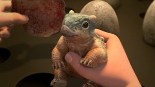 A freshly hatched Bumpy the Ankylosaurus smiles while being held in Jurassic World: Camp Cretaceous.