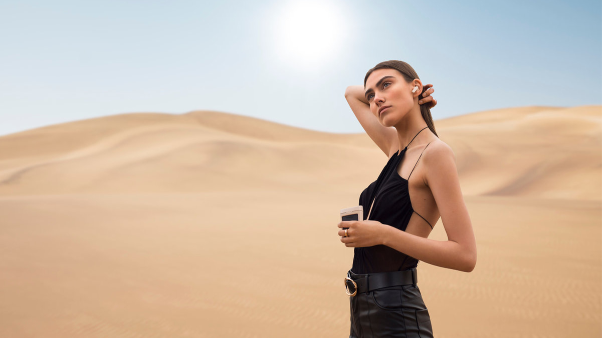Woman wearing the Urbanista Phoenix earbuds in a desert