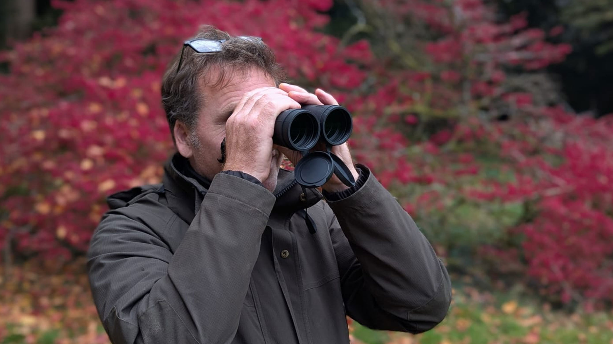 Our reviewer using the Carson VX 12x50 binoculars with autumn colours behind him.