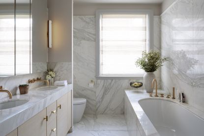 marble bathroom with brass fixtures by Kitesgrove