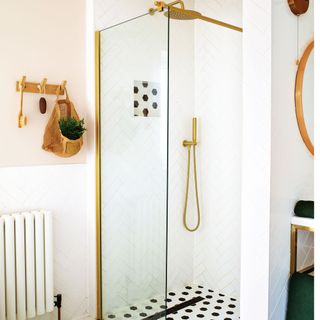 Walk-in shower with white metro herringbone tiles and gold coloured fittings