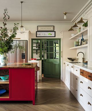 kitchen with white cabinetry and bright red kitchen island and wooden floors and green doors