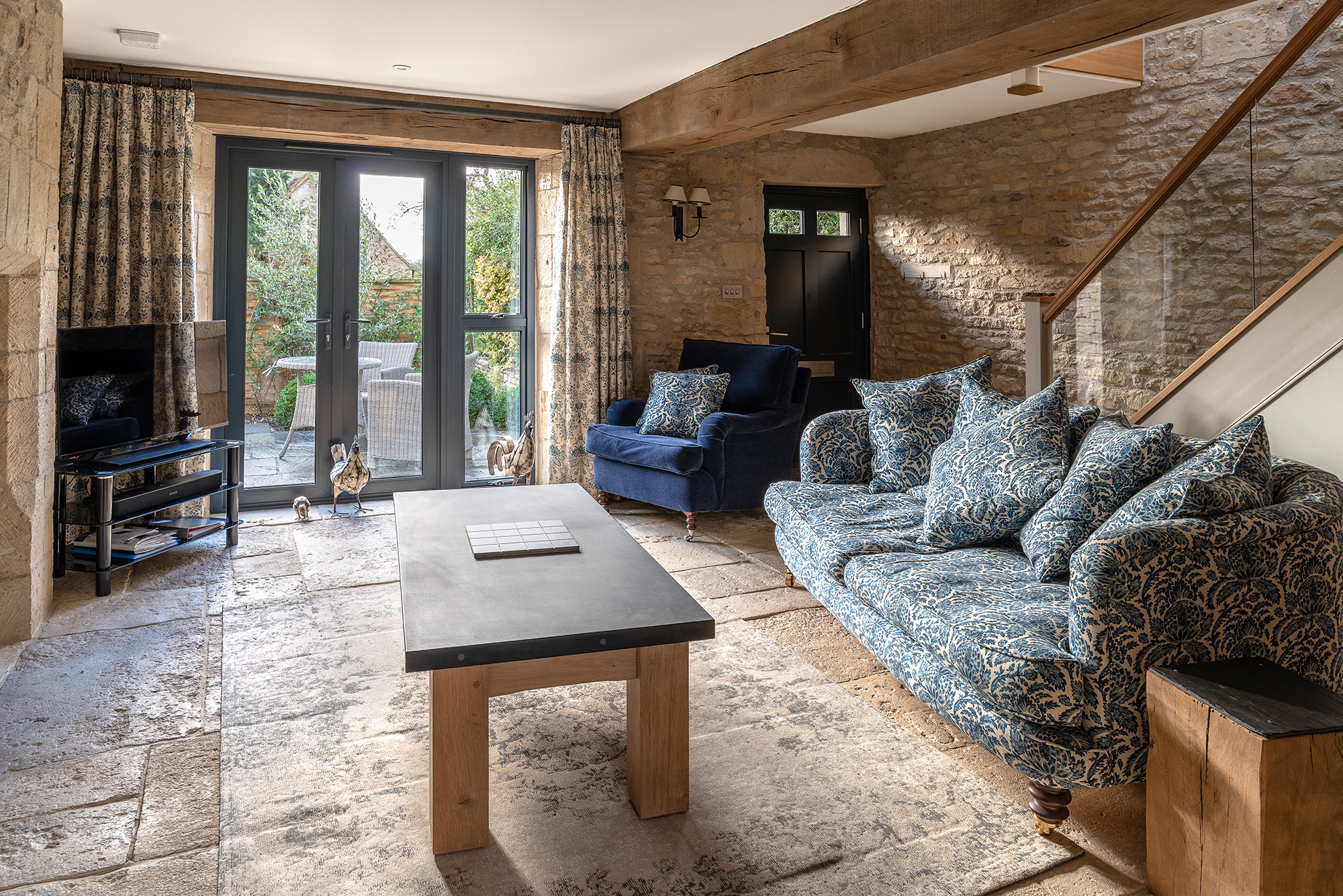Image of living room with stone walls with soft light flooding through French windows