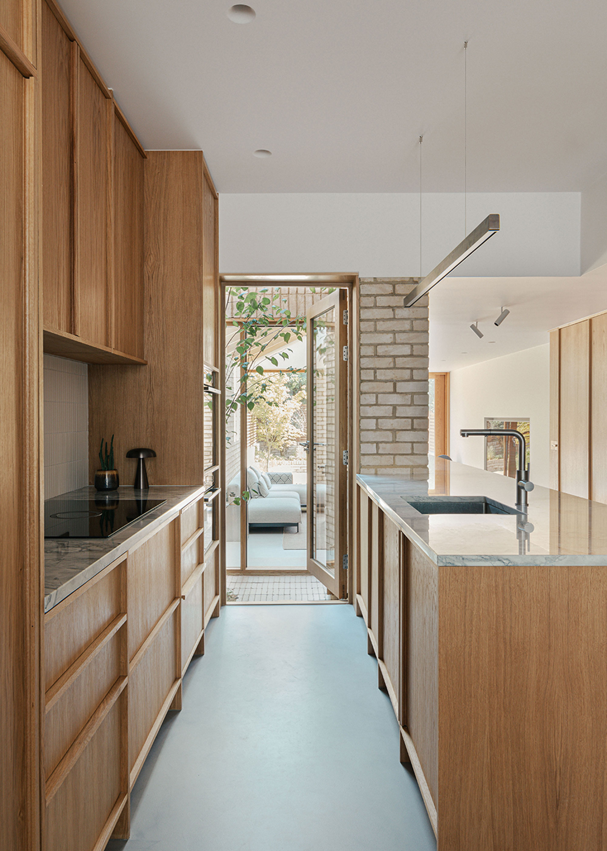 narrow kitchen with wooden kitchen cabinets and living room beyond