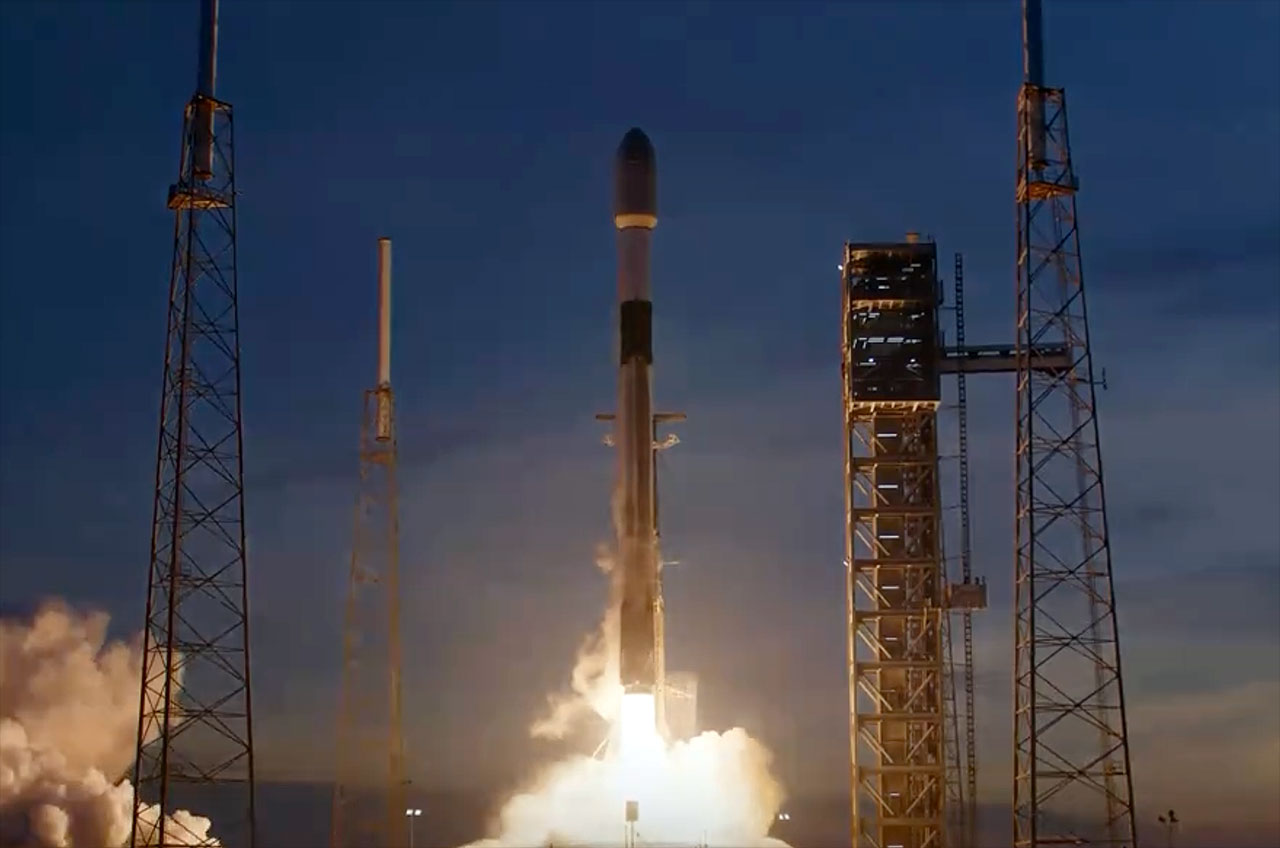a black and white rocket launches into a dusky blue sky.