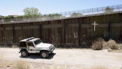 A border patrol agent drives past the U.S.-Mexico border wall.