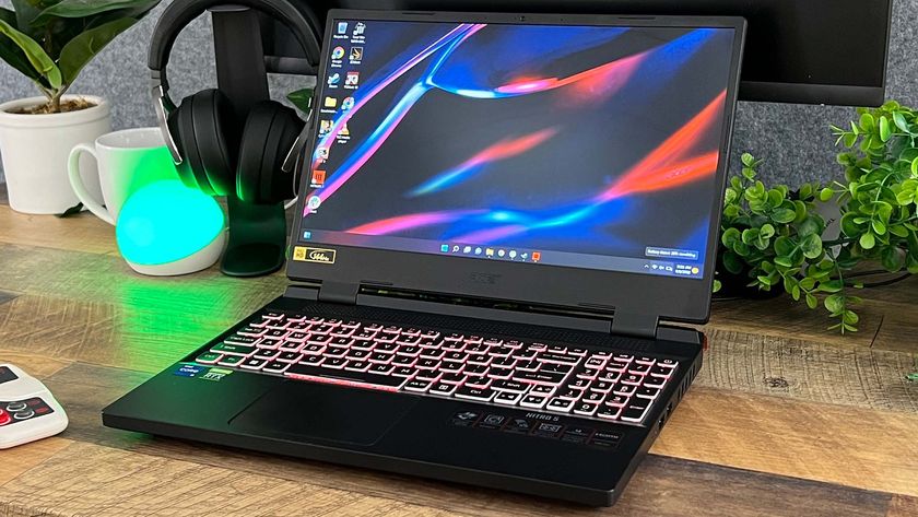 B&auml;sta billiga gaminglaptop: En Acer Nitro 5 st&aring;r &ouml;ppnad p&aring; ett tr&auml;f&auml;rgat skrivbord med en gr&ouml;n v&auml;xt och ett headset p&aring; sidorna.
