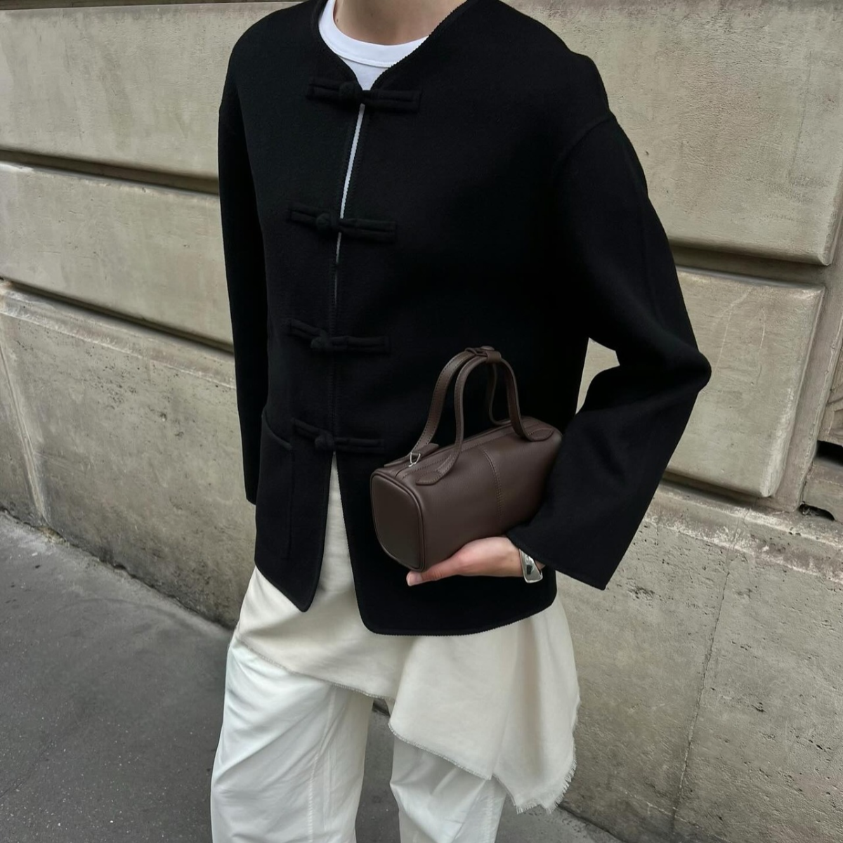 An image of an influencer wearing a black R&oacute;he jacket with white trousers and a white long shirt