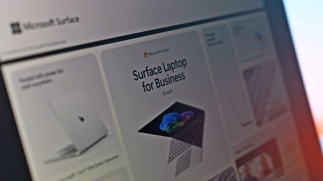Close-up of a computer screen displaying an advertisement for a "Surface Laptop for Business." The ad features a sleek laptop open with a colorful screen image. The tone is professional and modern.