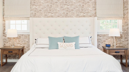 A bedroom with stone walls and light blue throw pillows