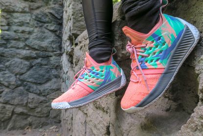 A pair of bright cross-trainers are shown against a rocky wall.