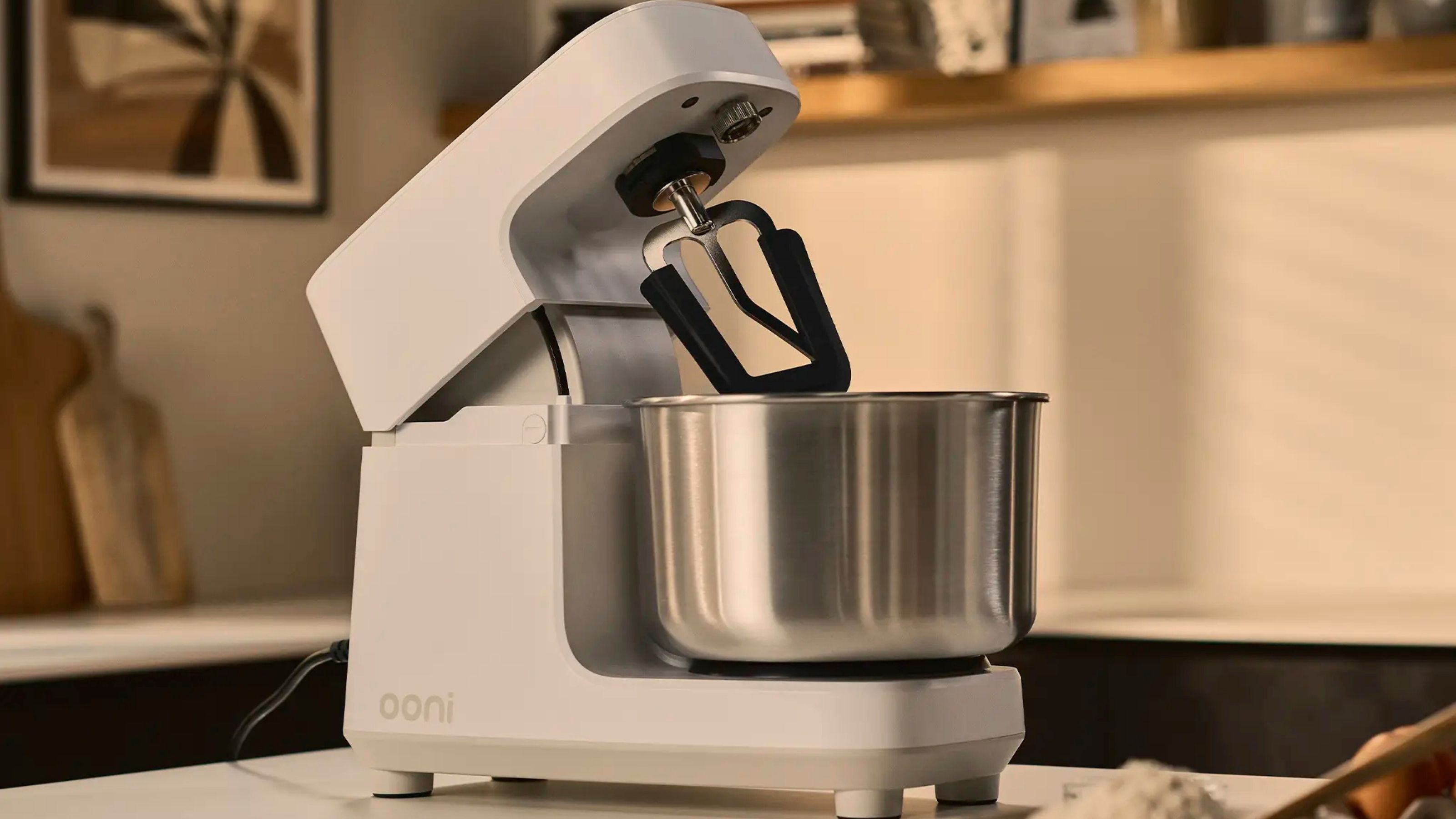 A white Ooni Halo Core Spiral Mixer on a kitchen counter, with the head tilted back. 