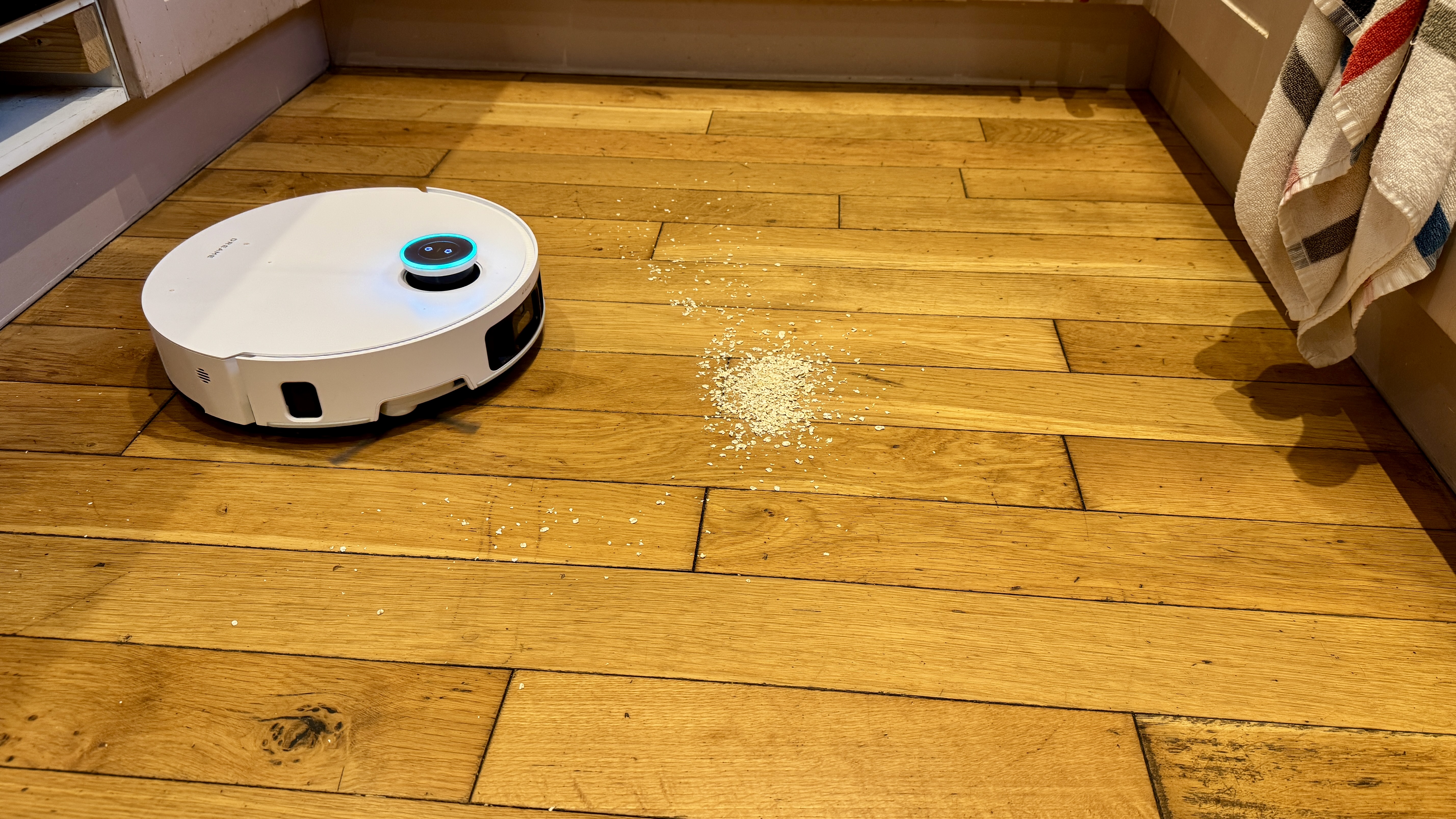 Dreame Matrix10 Ultra robot vacuum approaching a pile of oats on a wooden floor