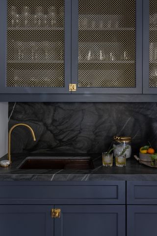 A navy kitchen cabinet with gold wire mesh panels