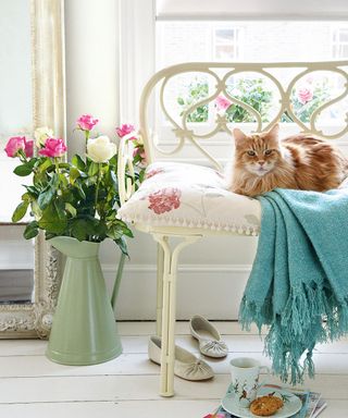 cat with pink flower vase and white pillow