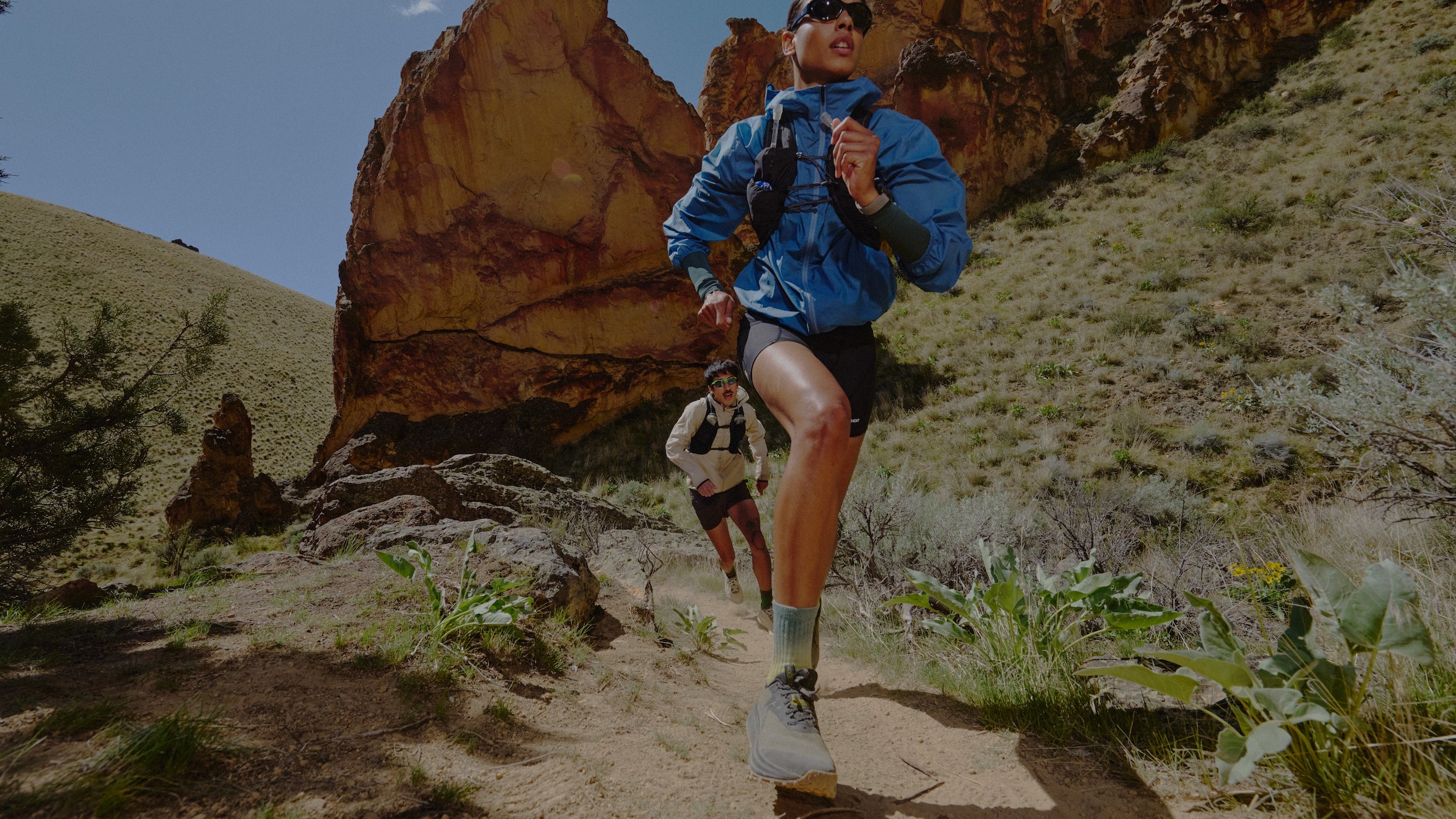 A woman and man running through the desert wearing the Keen Seek trail running shoe
