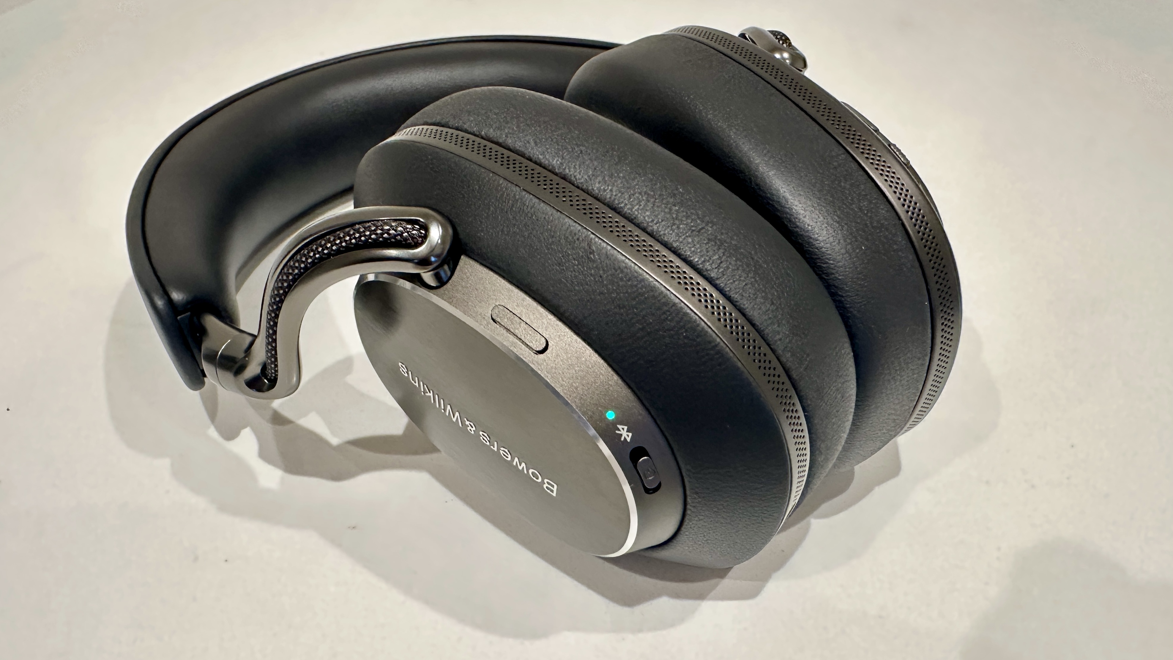 Bowers &amp;amp; Wilkins Px8 S2 over-ear headphones, with Bluetooth light on, on a white surface