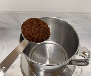 Vietnamese phin coffee maker with a scoop of ground coffee