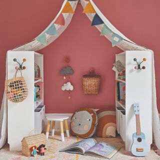 A children's playing den created from two bookshelves and a sheet draped on top