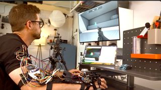 Man with DIY exoskeleton mounted on his forearm playing Aim Trainer.