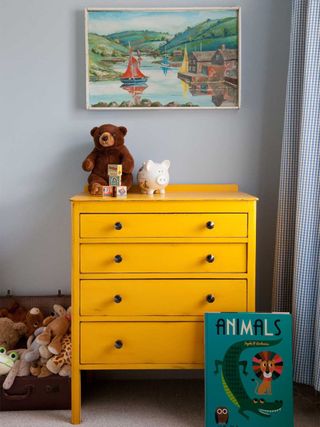 A child's bedroom with yellow painted chest of drawers