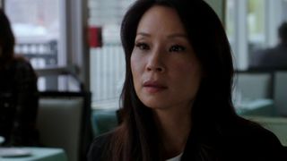 Lucy Lui sits at a booth in the show Elementary on Prime Video