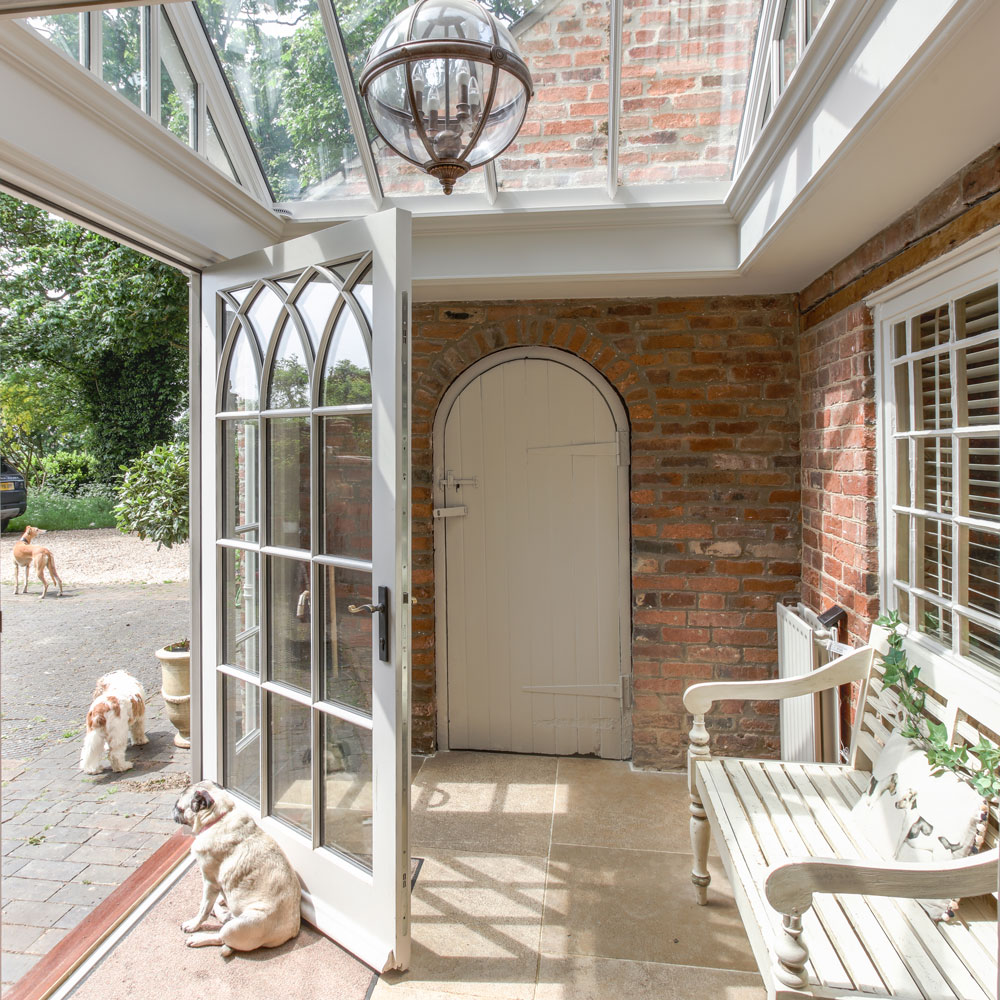 A conservatory with brick walls, a radiator and bench painted cream