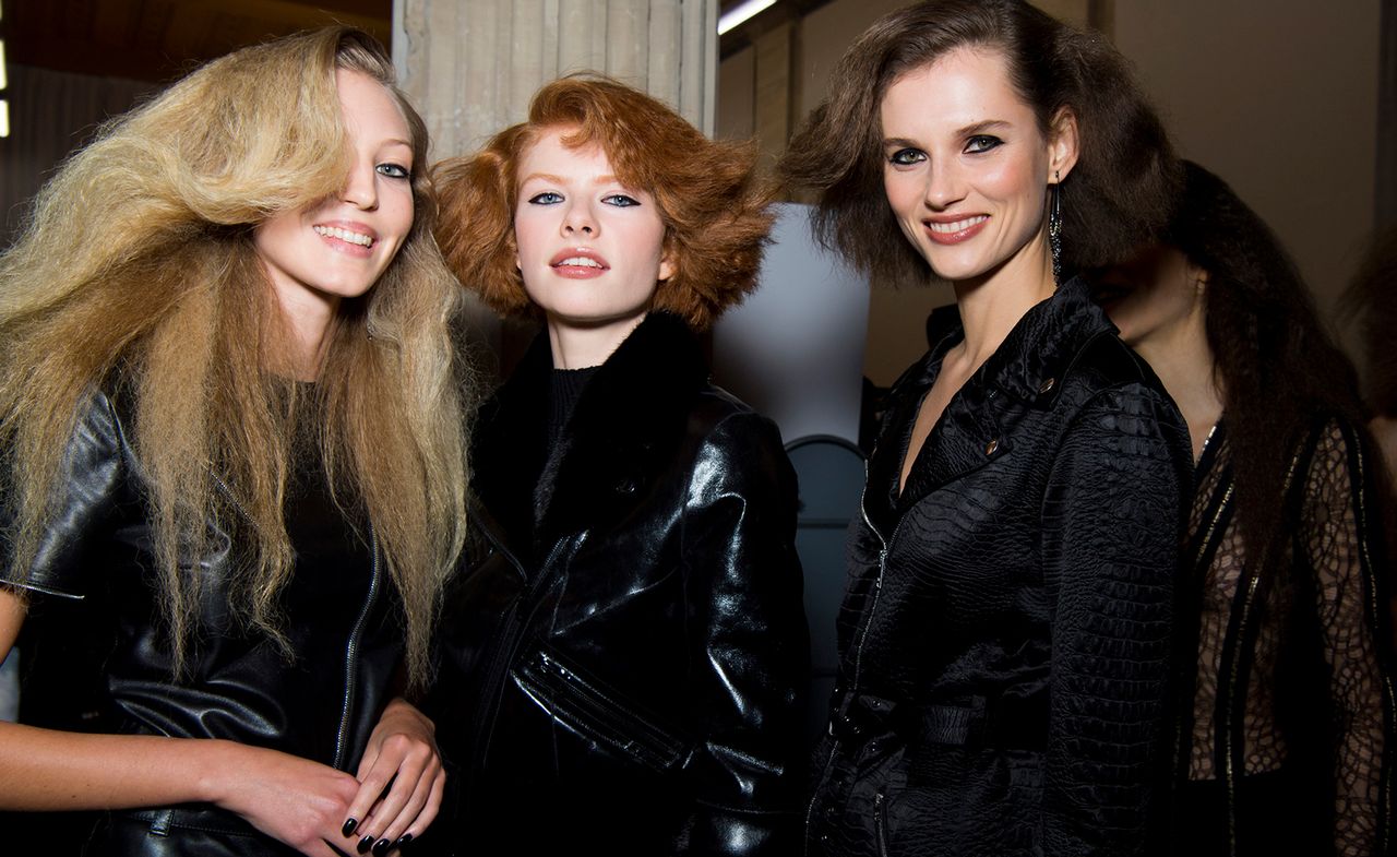 Models are seen wearing all-black outerwear, one model wears a patent jacket with fur lining, another wears a satin croc-print jacket, and other in a leather jacket