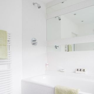 white bathroom with mirror on wall and bathtub