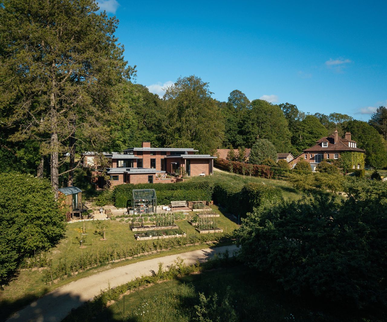 image showing brick eco cottage in gardens with larger house to one side