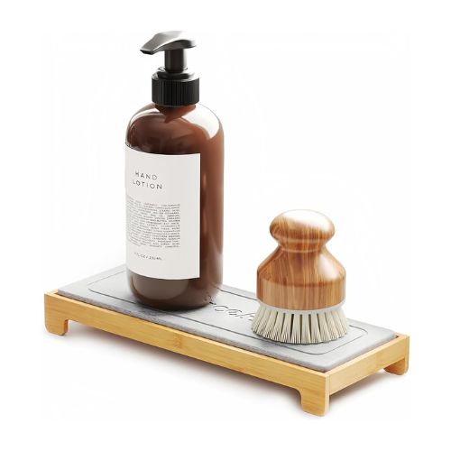 Raise rectangular stone drying mat with bamboo base and gray stone top with a bottle of hand lotion and small scrubbing brush with wooden handle sitting on top, white background.