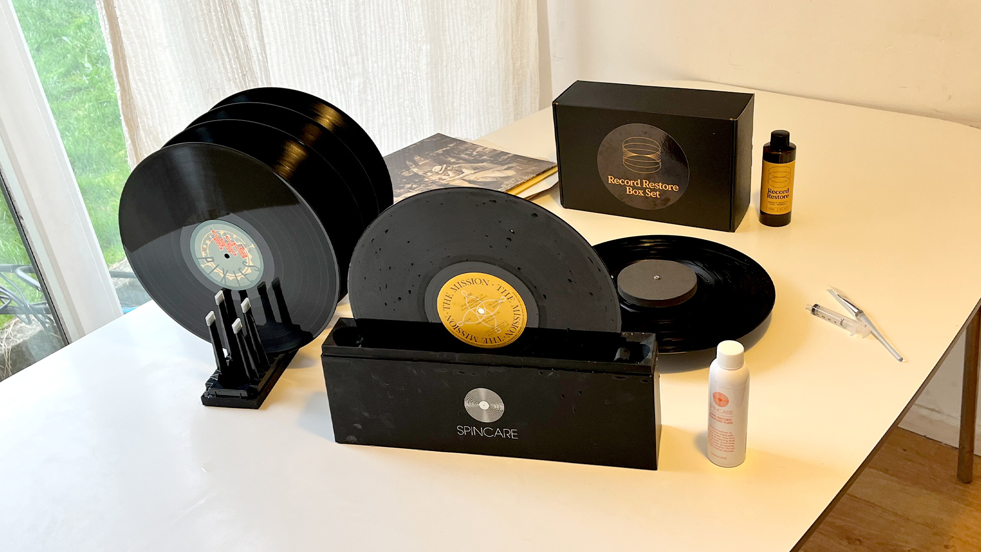Vinyl record cleaning kit and vinyl records on white table