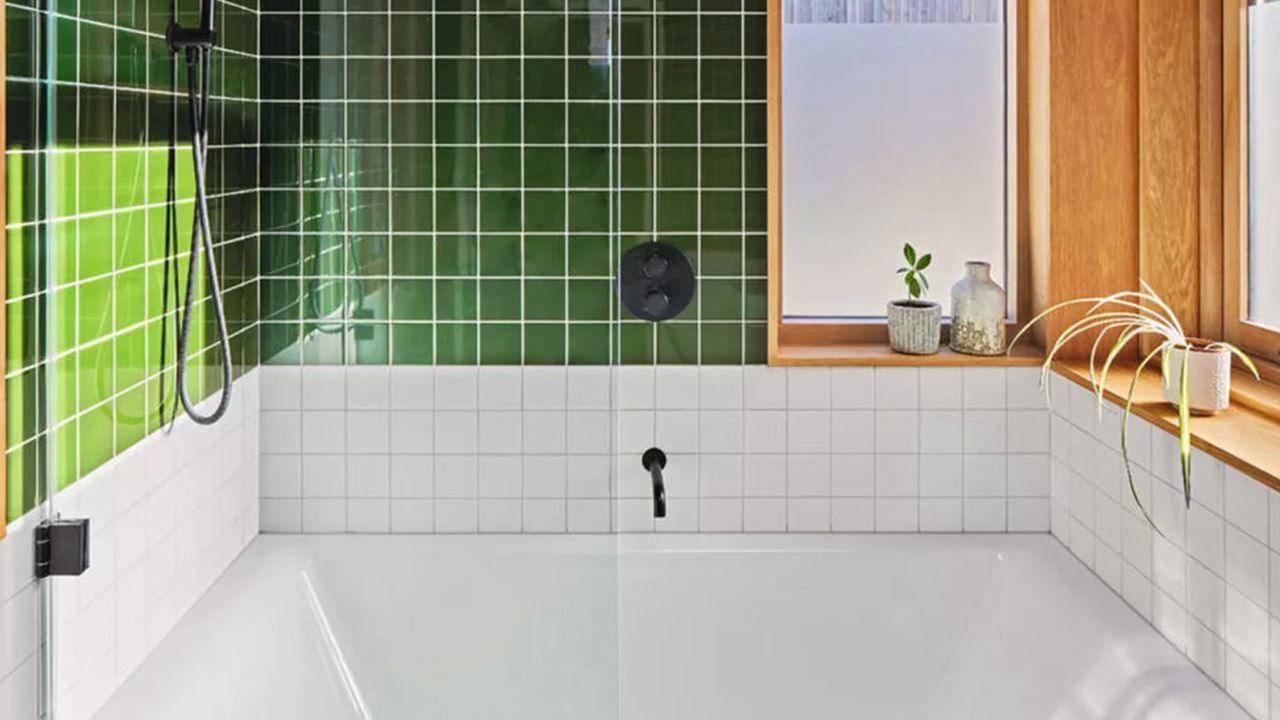 A green and white tiled bathroom with bathtub