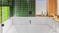A green and white tiled bathroom with bathtub