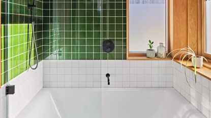 A green and white tiled bathroom with bathtub