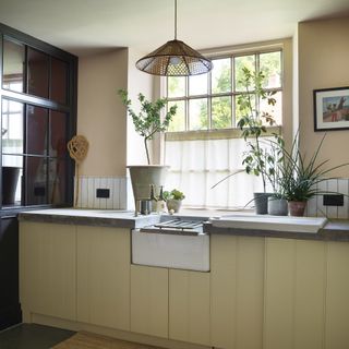 Kitchen with pendant light and white linen cafe curtains on window.