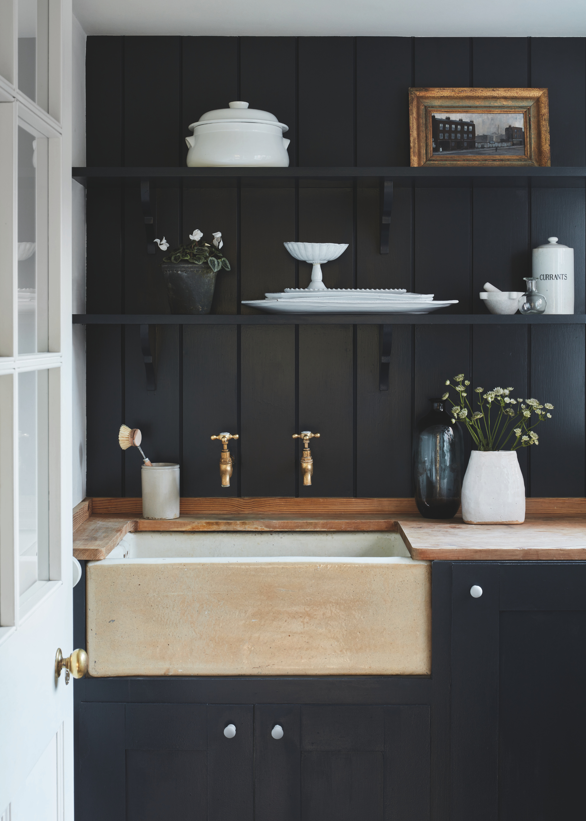 kitchen sink in a rustic home with wooden countertops and dark, navy panelled walls and cabinets