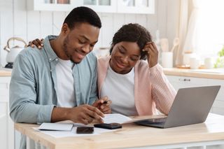 couple looking at household bills in front of laptop at home