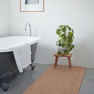 modern bathroom with sisal rug and wooden stool with plant on