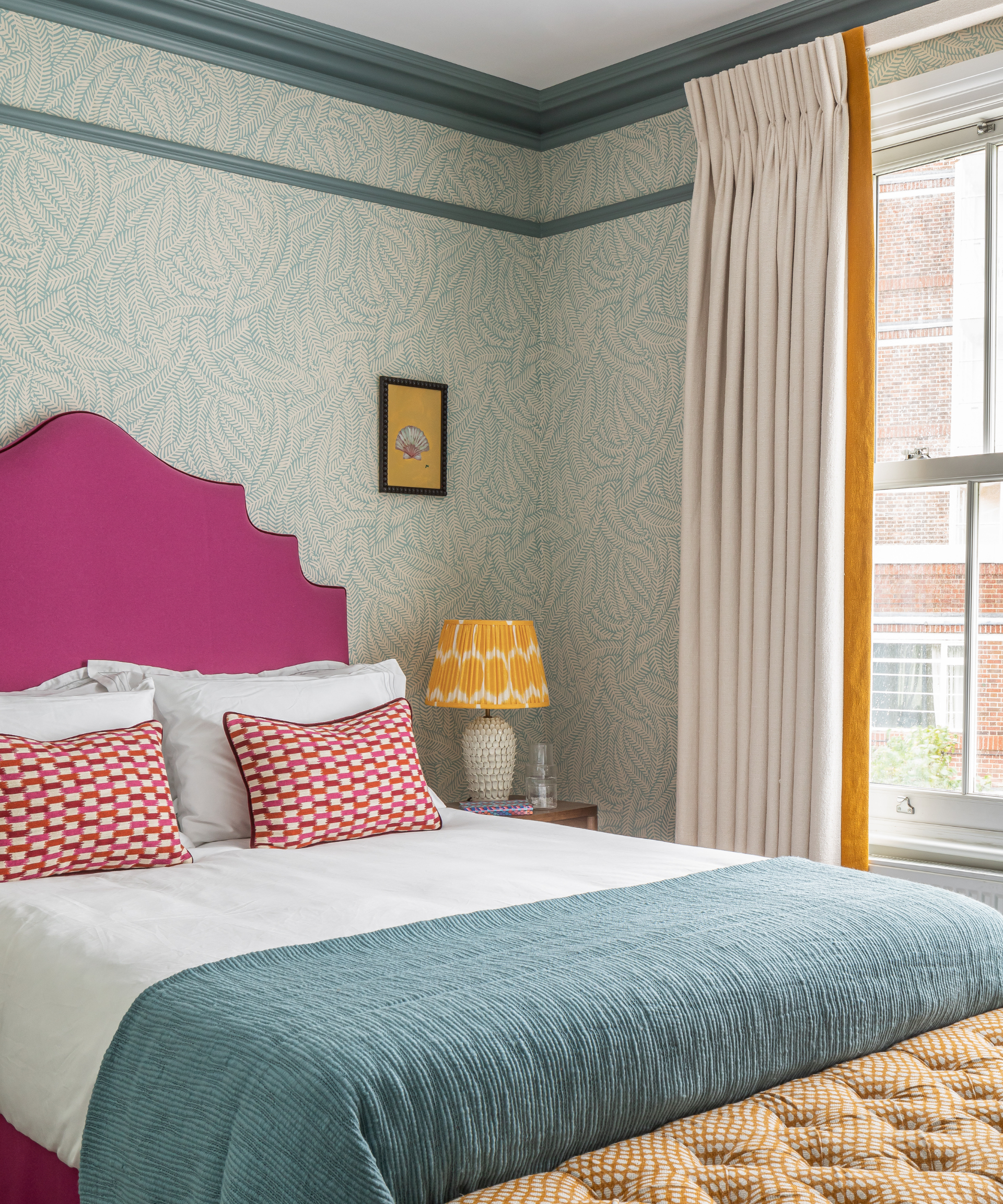 A blue bedroom with a bright pink headboard