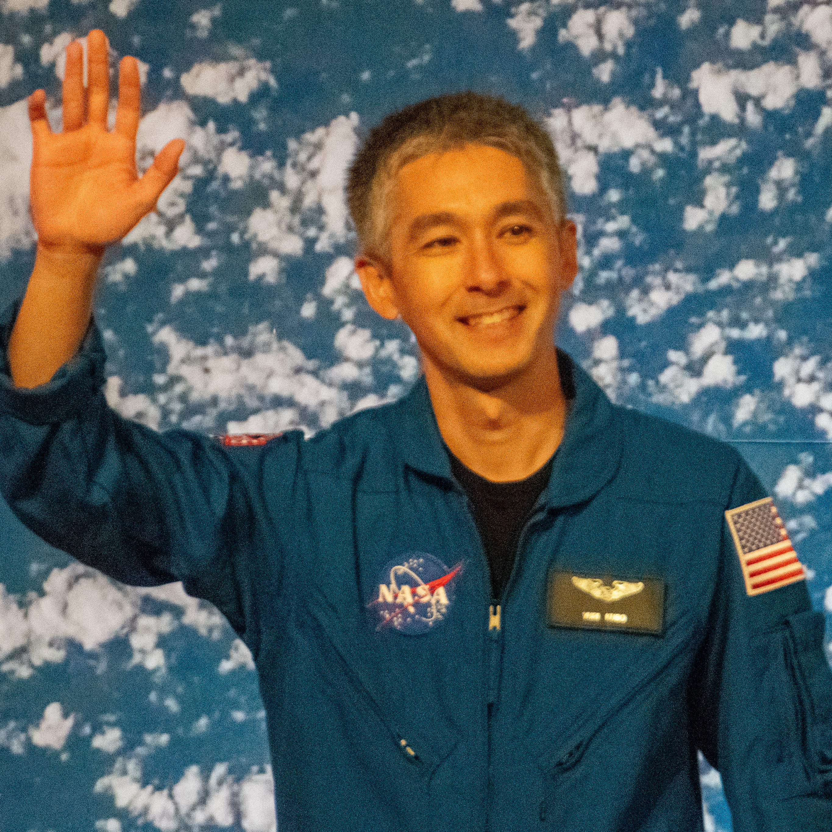 people in blue jumpsuits smile and wave.