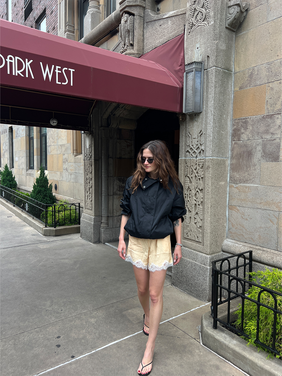 Eliza Huber wearing lace-trim shorts with a sporty black jacket and heeled flip flops.